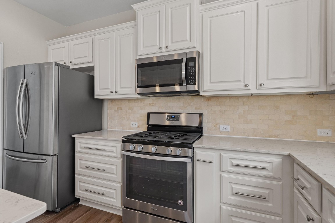 9416 Hunter Lane Austin, TX 78748 - Photo 12 of 35 a kitchen with stainless steel appliances white cabinets and a stove a refrigerator with wooden floors