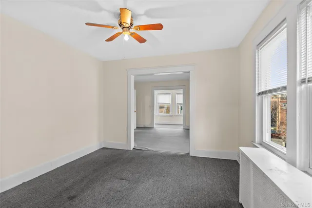 an empty room with chandelier fan and windows