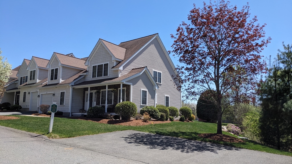 a front view of a house with a garden and trees