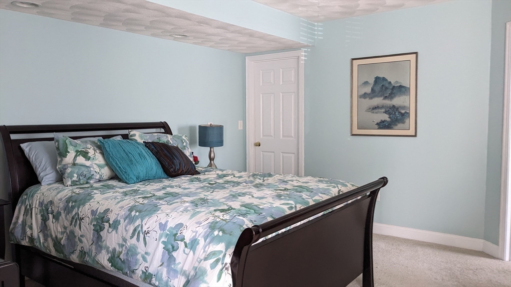 53 Baldwin Road, Unit 201 Billerica, MA 01821 - Photo 16 of 35 a bed sitting in a bedroom next to a wooden cabinet