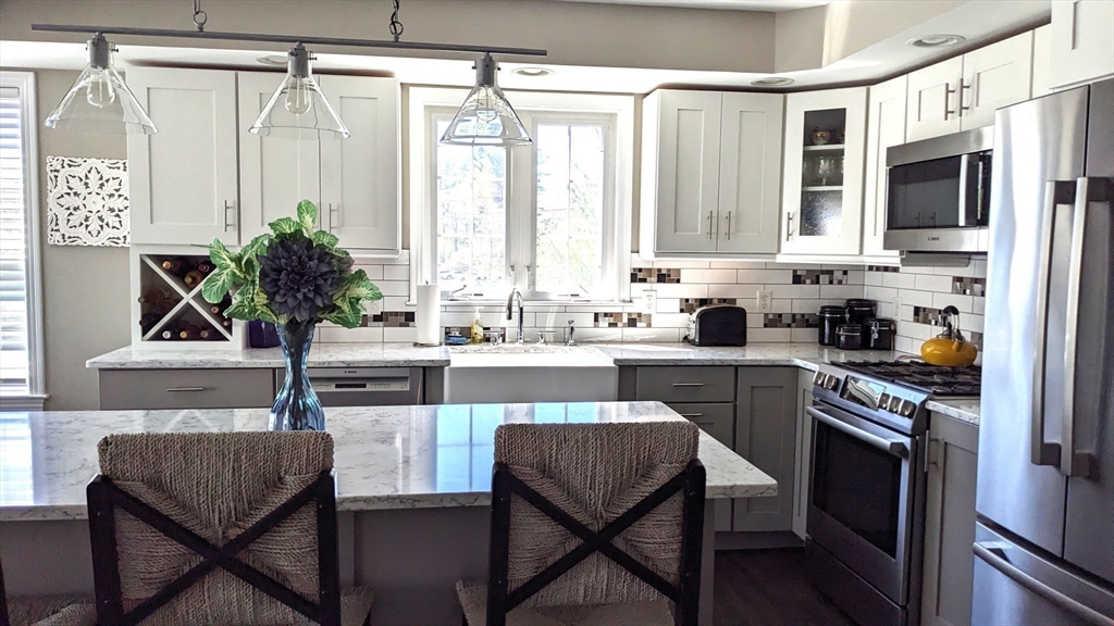 53 Baldwin Road, Unit 201 Billerica, MA 01821 - Photo 7 of 35 a kitchen with stainless steel appliances a table chairs and a refrigerator