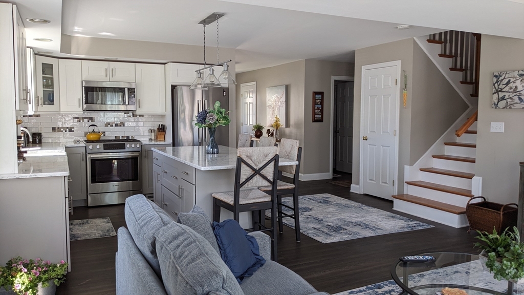 53 Baldwin Road, Unit 201 Billerica, MA 01821 - Photo 10 of 35 a kitchen with stainless steel appliances kitchen island granite countertop a refrigerator oven a sink a dining table and chairs with wooden floor