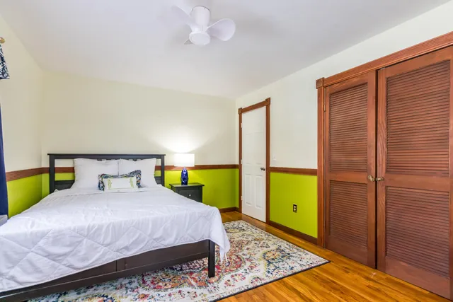 a bedroom with a bed a mirror on the dresser and a wooden floor