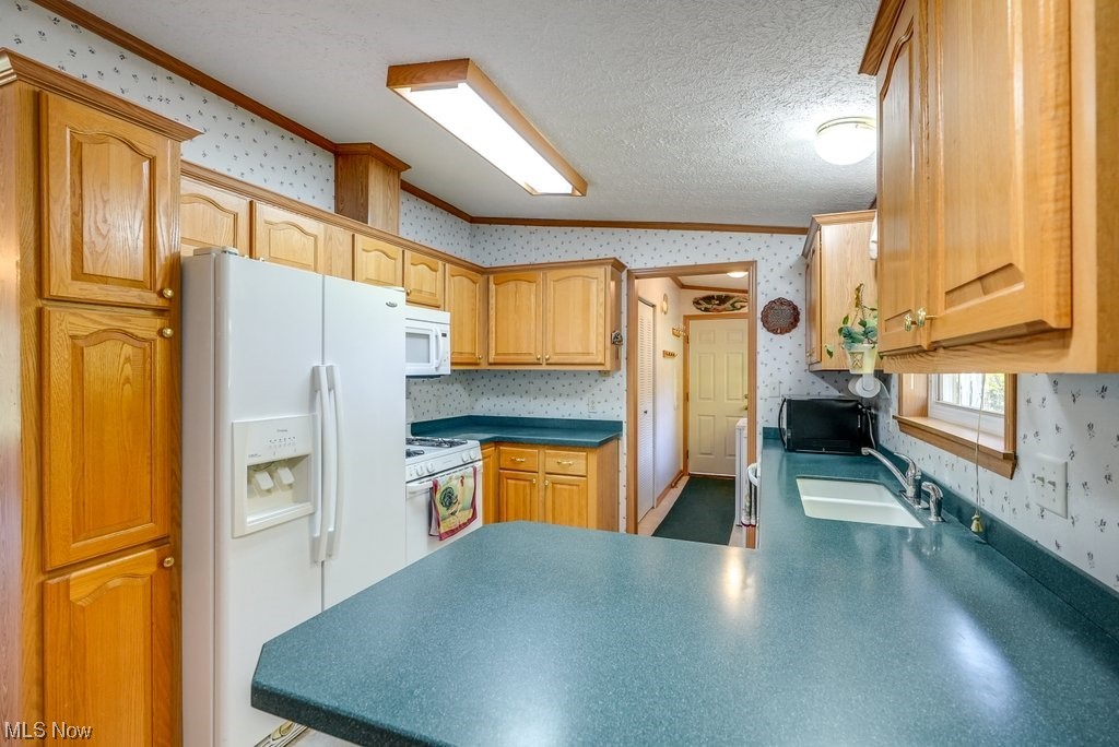 1189 Sandy Lake Road Ravenna, OH 44266 - Photo 19 of 32 Kitchen with sink, white appliances, vaulted ceiling, a textured ceiling, and kitchen peninsula