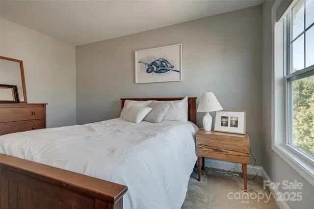 a bedroom with a bed a dresser and next to a window