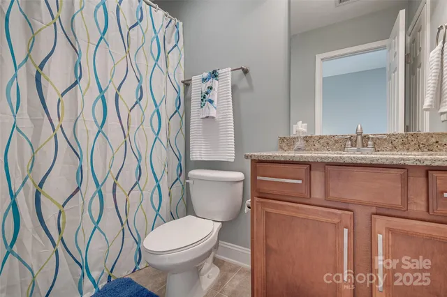 a bathroom with a granite countertop toilet sink and mirror
