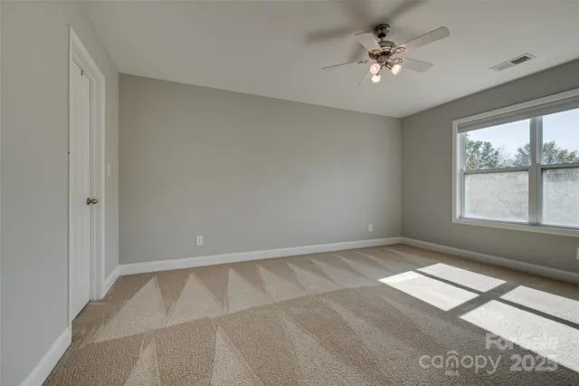 an empty room with windows and ceiling fan