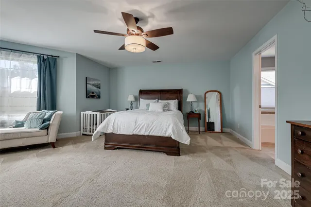 a spacious bedroom with a bed a couch and a large window