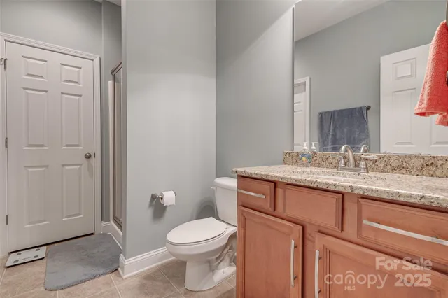 a bathroom with a granite countertop toilet a sink and a mirror