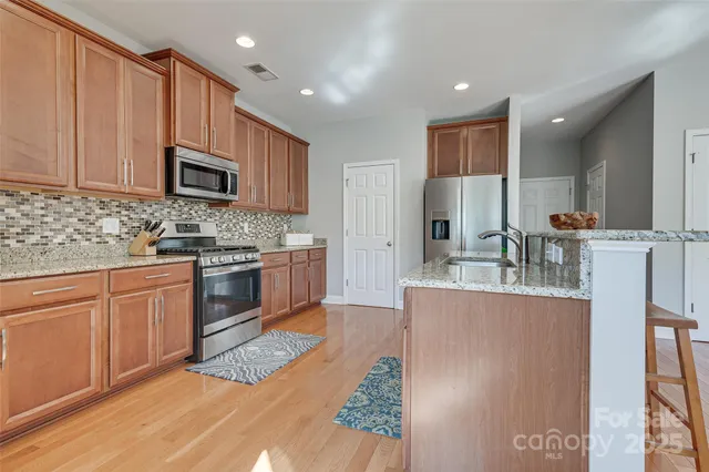 a kitchen with stainless steel appliances granite countertop a stove top oven a sink a counter space and cabinets