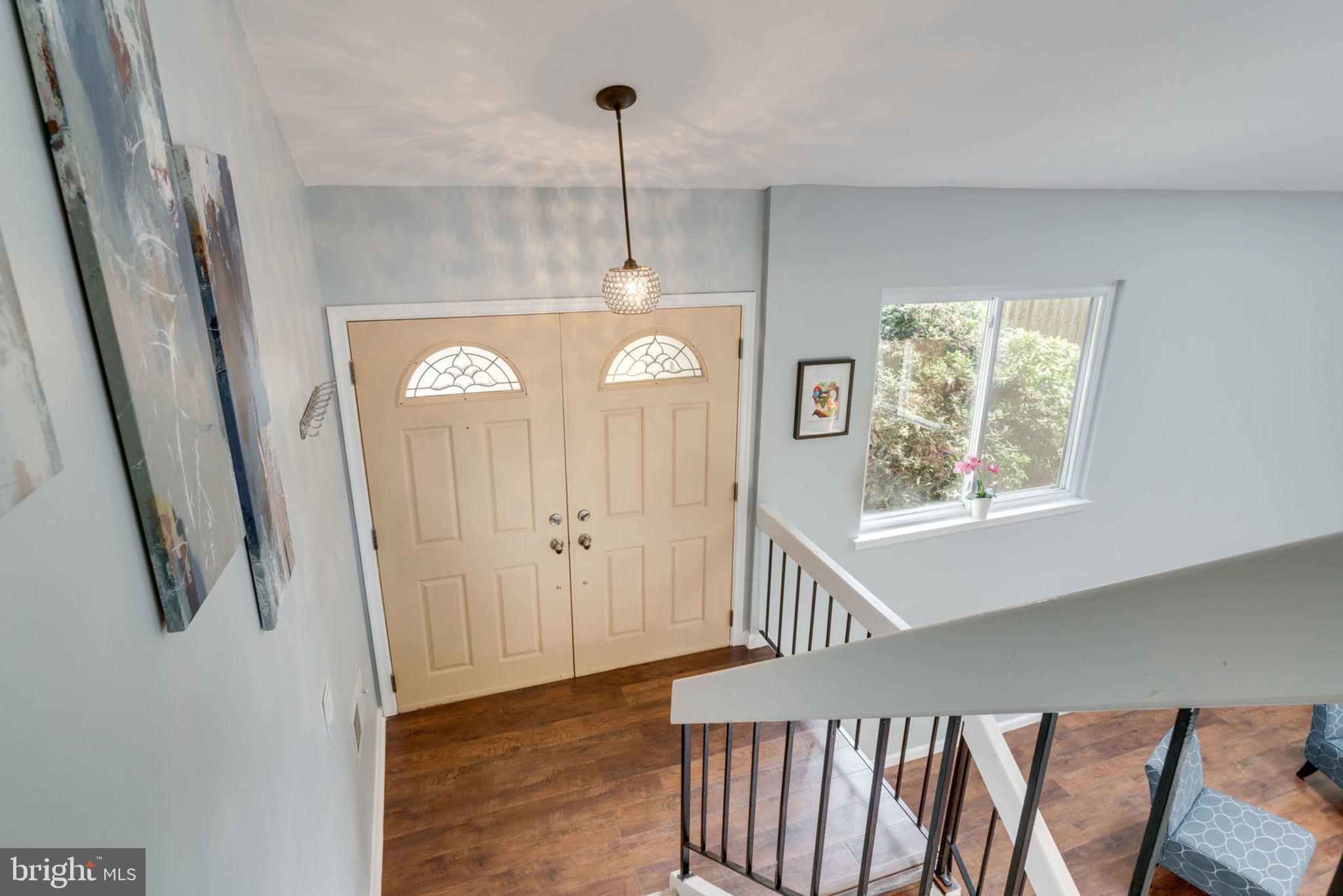 7627 Mineral Spring Court Springfield, VA 22153 - Photo 7 of 34 a view of a hallway to a livingroom with furniture wooden floor windows and a chandelier