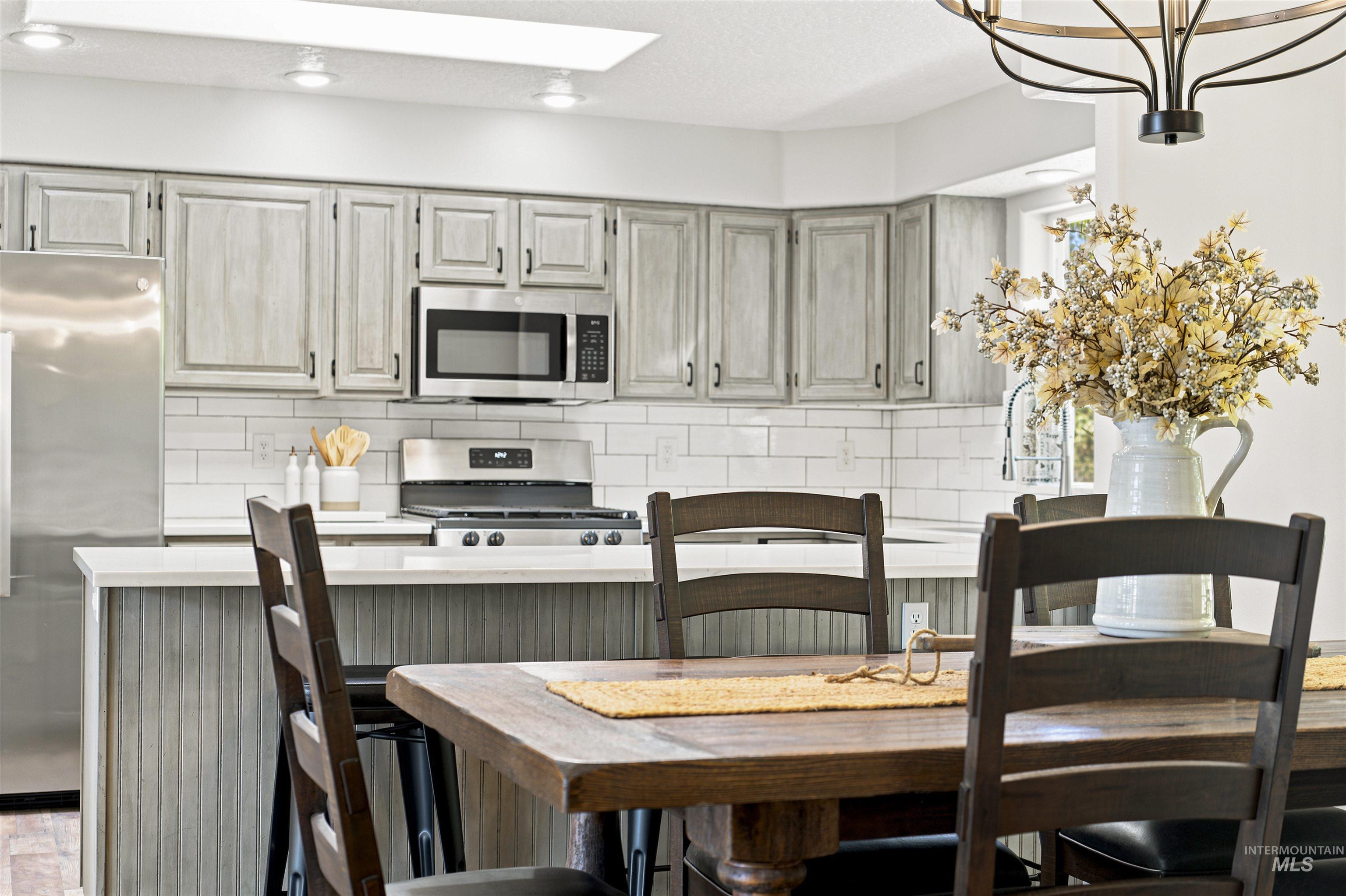 24864 Coventry Drive Caldwell, ID 83607 - Photo 10 of 49 Kitchen and dining area featuring light-toned cabinetry, stainless steel appliances, and white subway tile backsplash