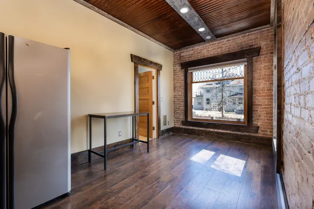 an empty room with wooden floor a ceiling fan and windows