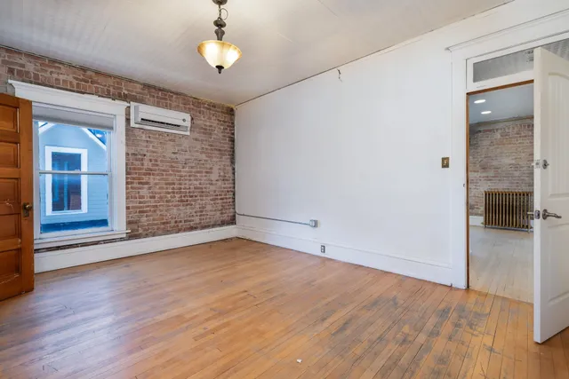an empty room with wooden floor chandelier and windows