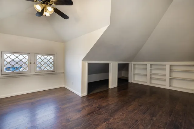 an empty room with wooden floor chandelier and windows