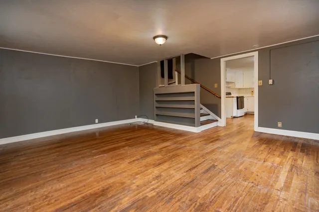 a view of empty room with wooden floor and window