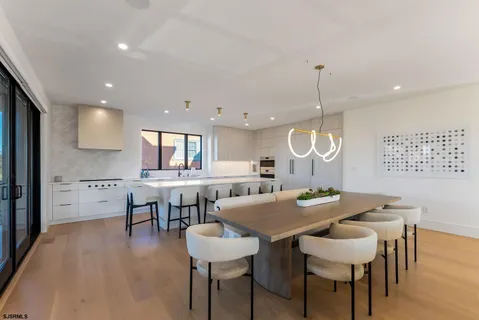 a kitchen with stainless steel appliances kitchen island granite countertop a table chairs sink and cabinets