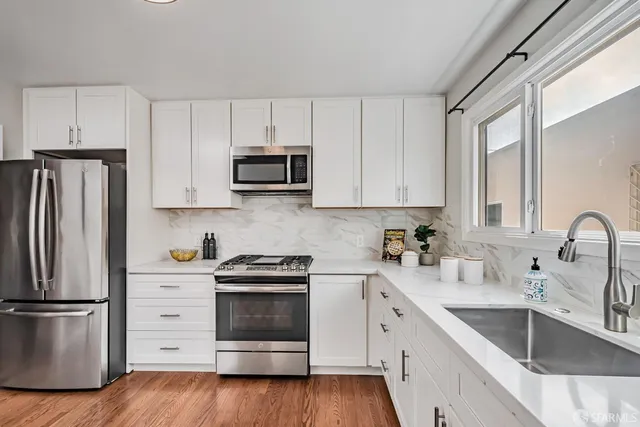 a kitchen with cabinets stainless steel appliances a sink and wooden floor