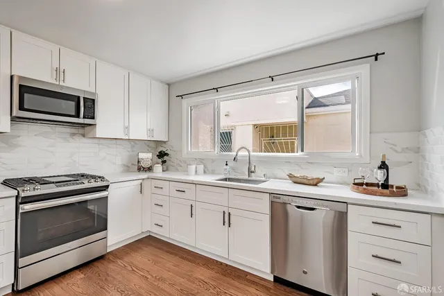 a kitchen with cabinets stainless steel appliances a sink and a window
