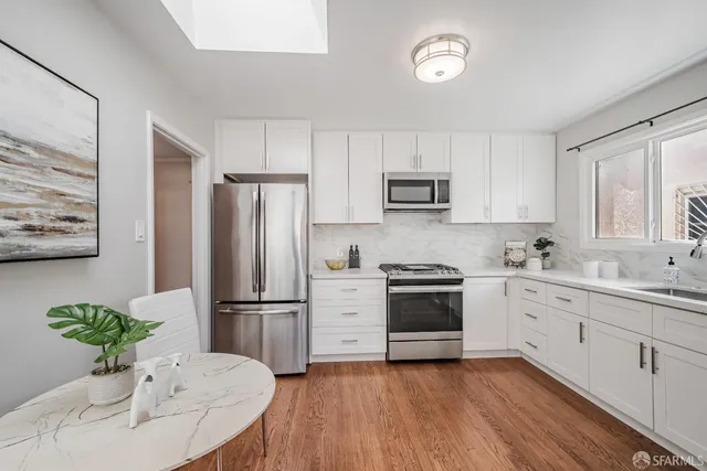 a kitchen with stainless steel appliances a refrigerator sink and white cabinets