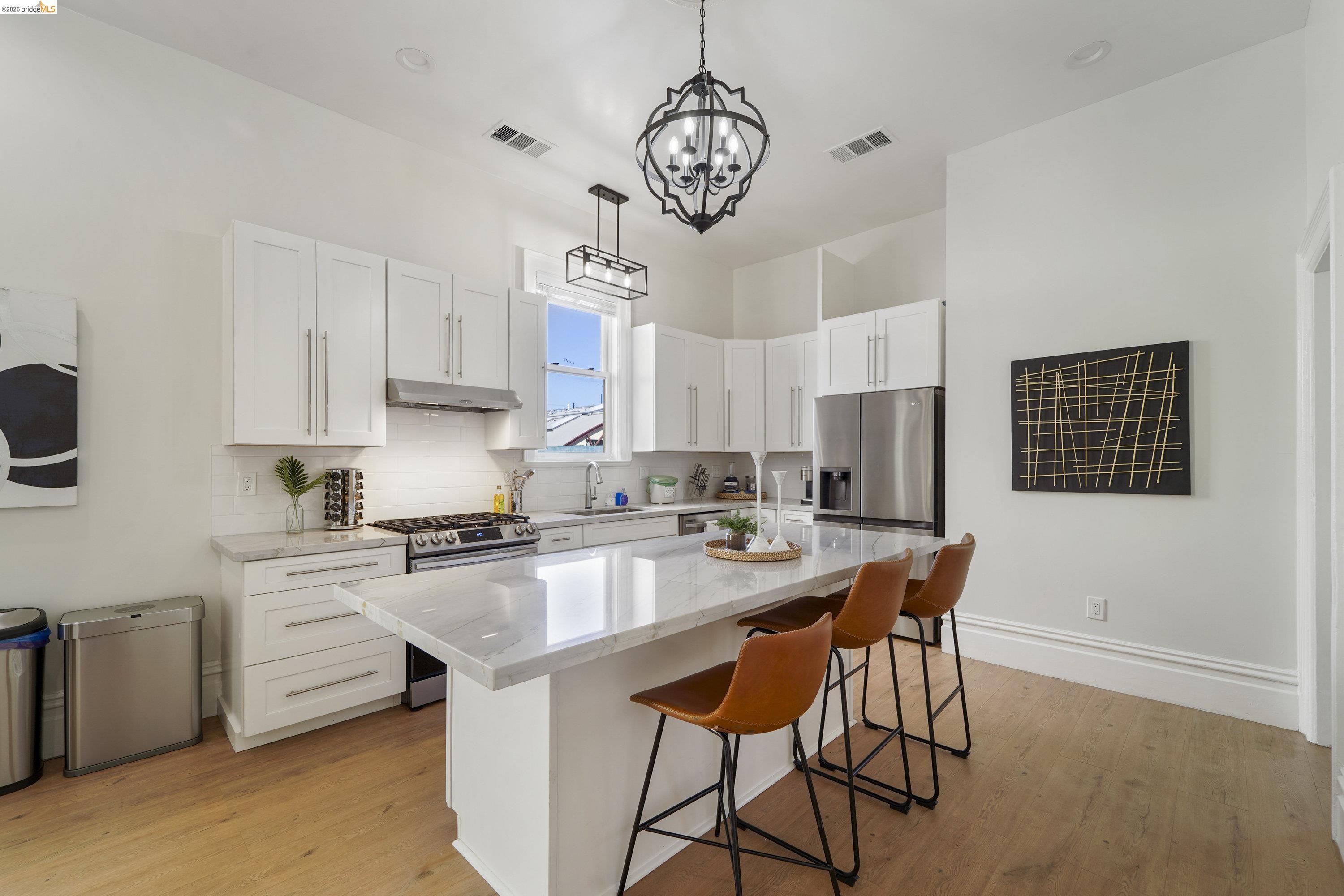 1662 14th Street Oakland, CA 94607 - Photo 16 of 57 a open kitchen with stainless steel appliances granite countertop a stove top oven a refrigerator a sink dishwasher a dining table and chairs with wooden floor
