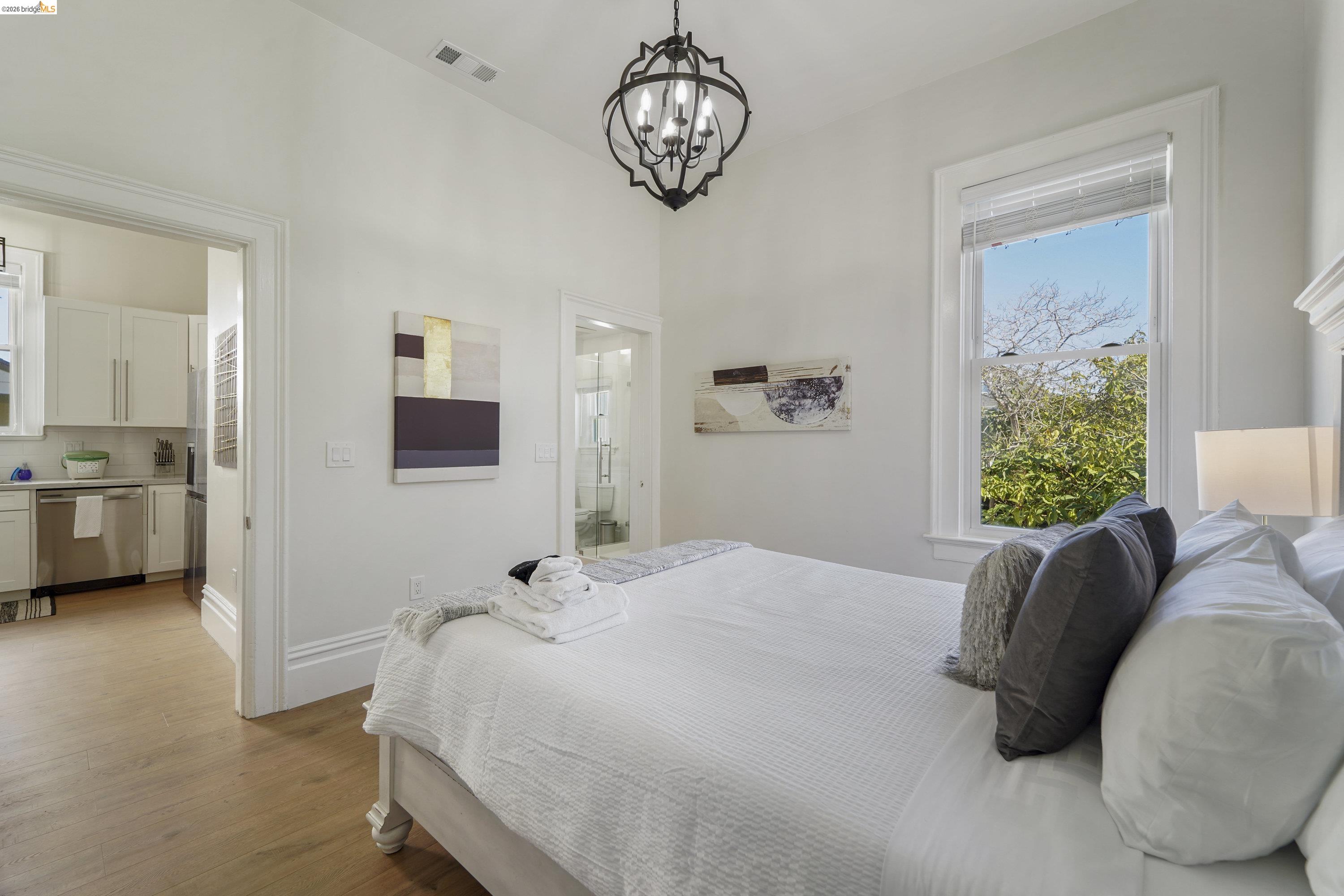 1662 14th Street Oakland, CA 94607 - Photo 21 of 57 a bedroom with a bed chandelier and a window
