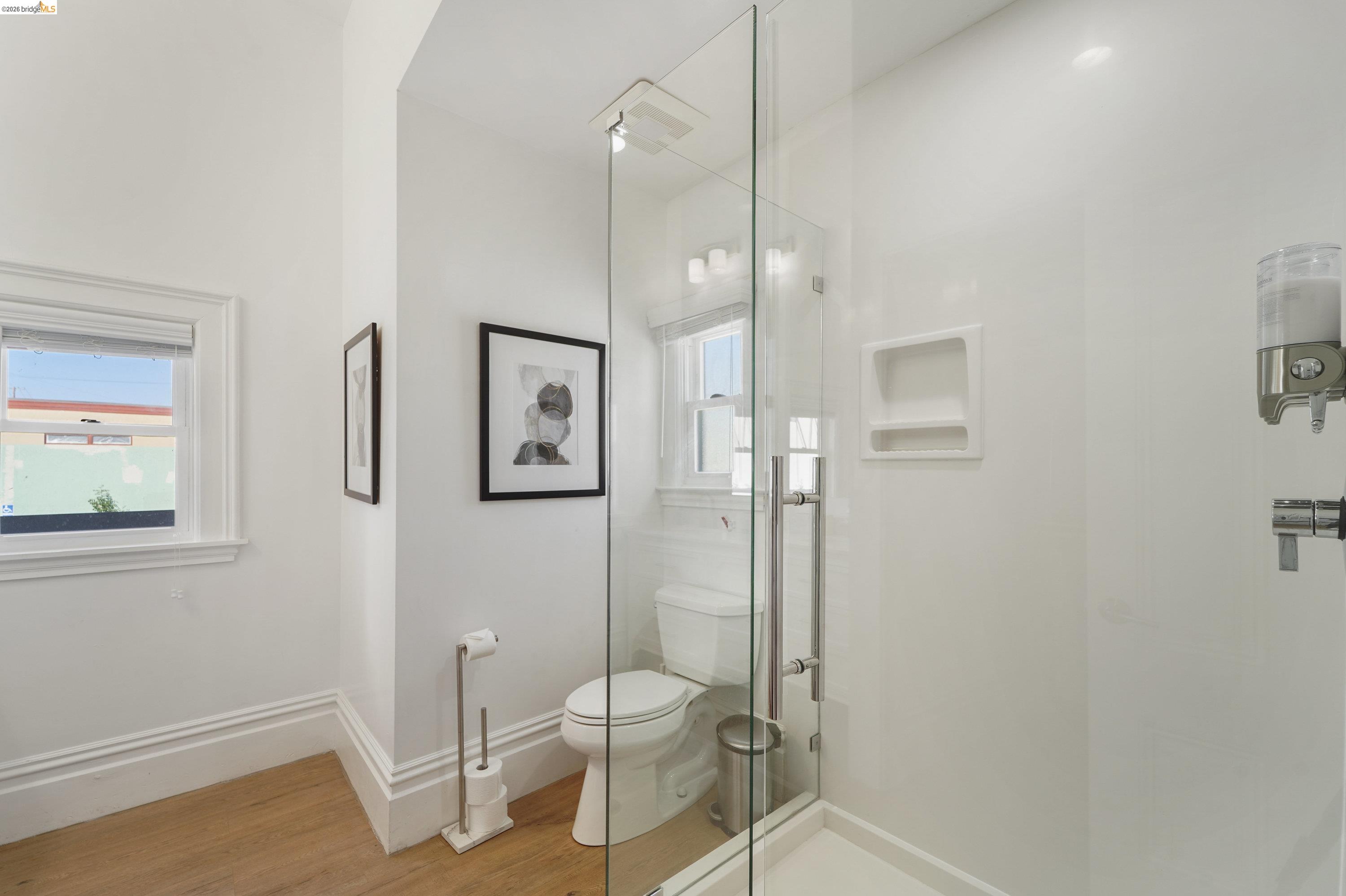 1662 14th Street Oakland, CA 94607 - Photo 24 of 57 a bathroom with a glass shower door and a toilet