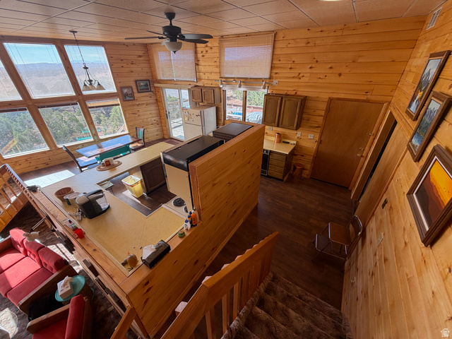 358 South Sky Drive Torrey, UT 84775 - Photo 23 of 82 Open-concept living area featuring extensive wood paneling, a ceiling fan with integrated lighting, and a prominent kitchen counter with a built-in cooktop