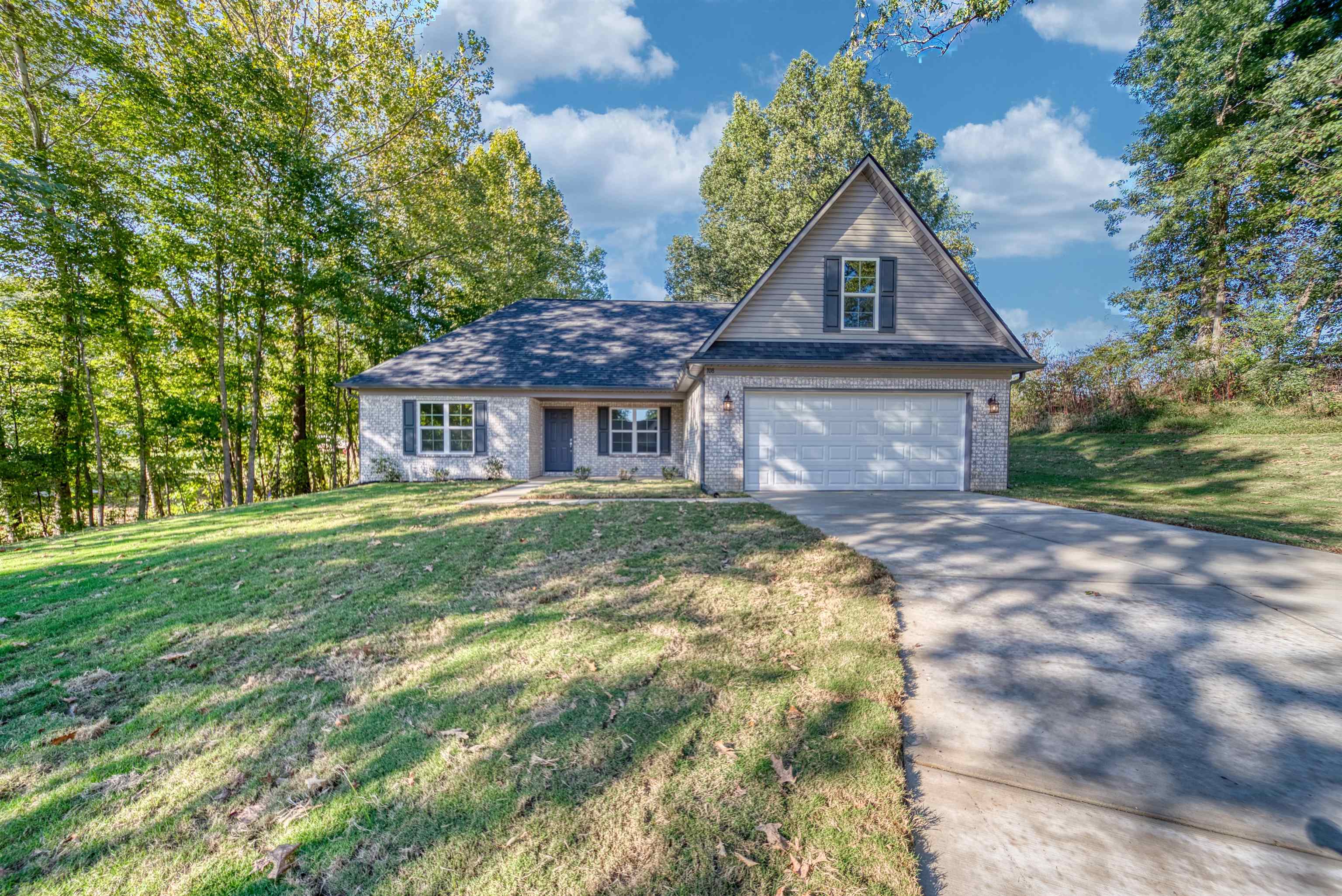 Traditional-style home with driveway, a front lawn, a garage, and brick siding