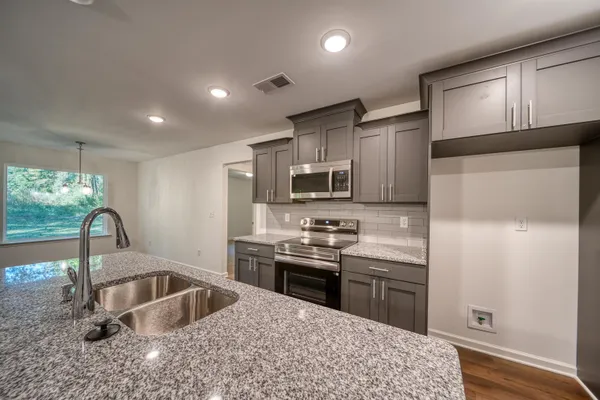 a kitchen with stainless steel appliances granite countertop a sink stove and refrigerator