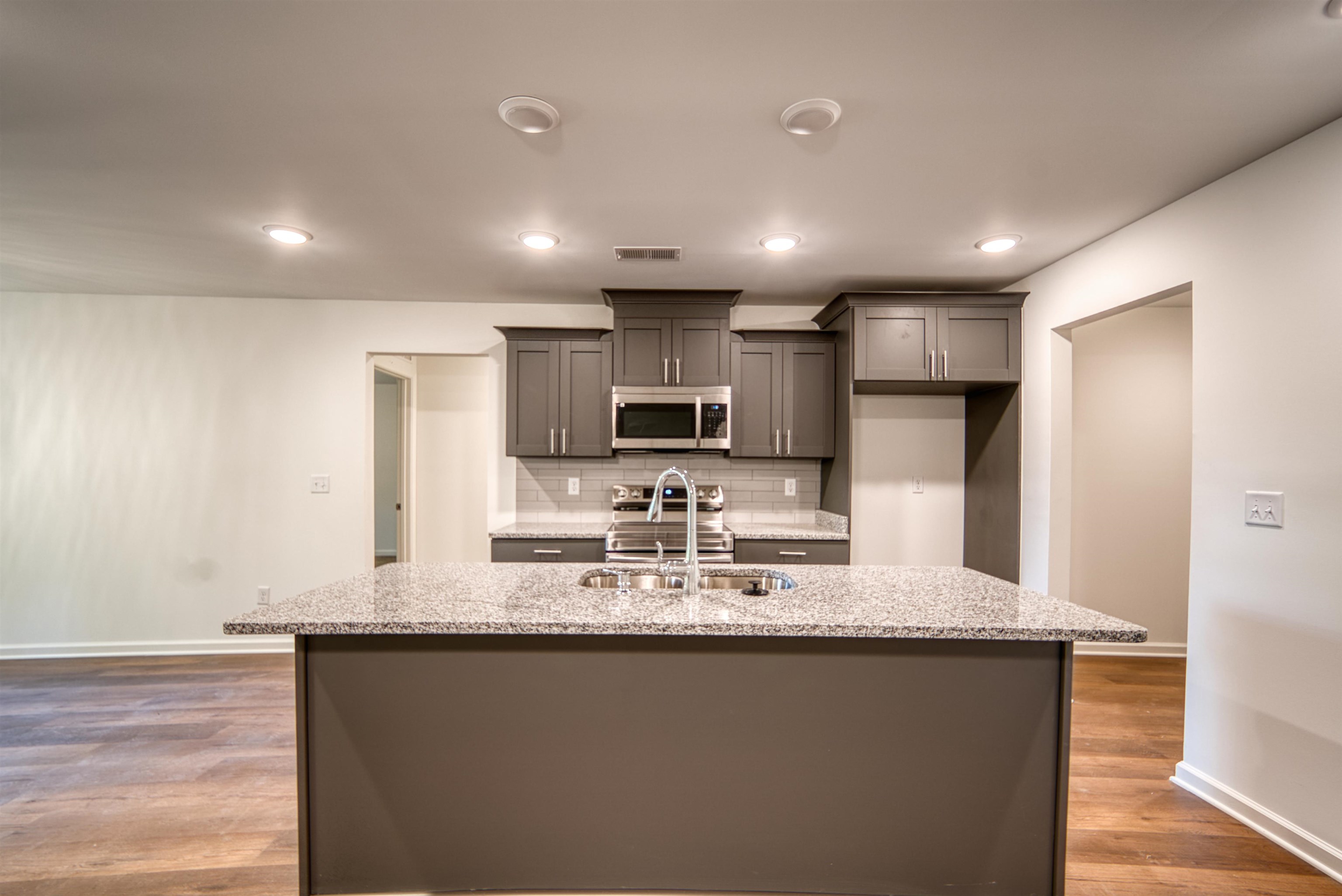 108 Walnut Ridge Ripley, TN 38063 - Photo 33 of 35 Kitchen featuring light stone countertops, gray cabinets, decorative backsplash, stainless steel appliances, and a center island with sink