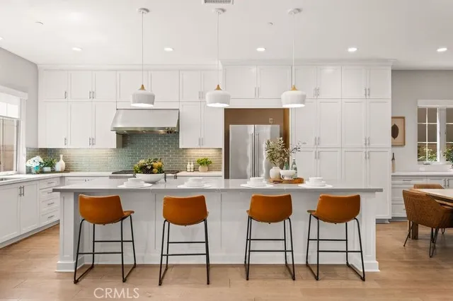 a kitchen with stainless steel appliances granite countertop a table chairs sink and cabinets