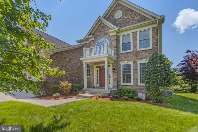 a view of a brick house with a yard potted plants and a table chair