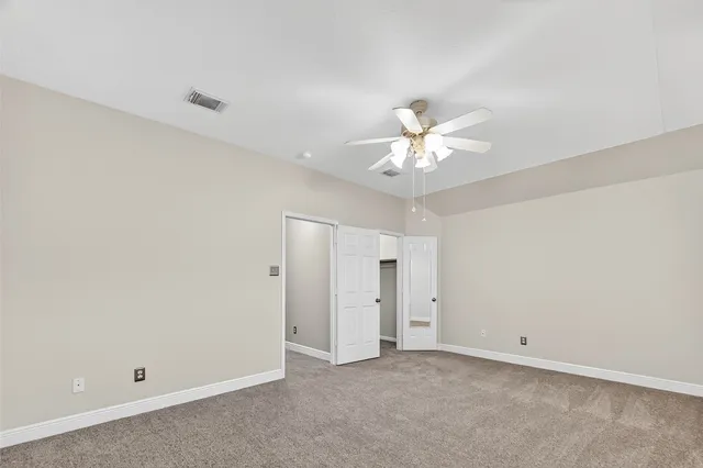an empty room with chandelier fan and a ceiling fan