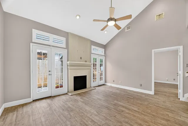 a view of an empty room with wooden floor fireplace and a window