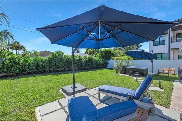 a backyard of a house with table and chairs under an umbrella