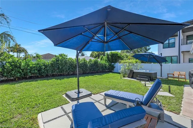 a backyard of a house with table and chairs under an umbrella