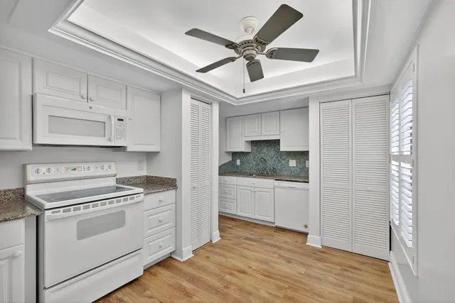 a kitchen with a stove white cabinets and white appliances