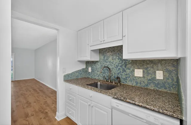 a kitchen with stainless steel appliances granite countertop a sink and white cabinets