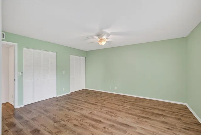 a view of a big room with wooden floor and a chandelier fan