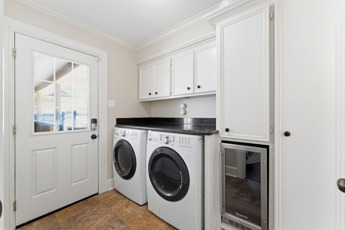 20 Falling Star Road The Woodlands, TX 77381 - Photo 18 of 44 A bright, functional laundry room featuring a washer, dryer, and a mini fridge. It has white cabinetry for storage and a door with glass panels leading outside, providing natural light.