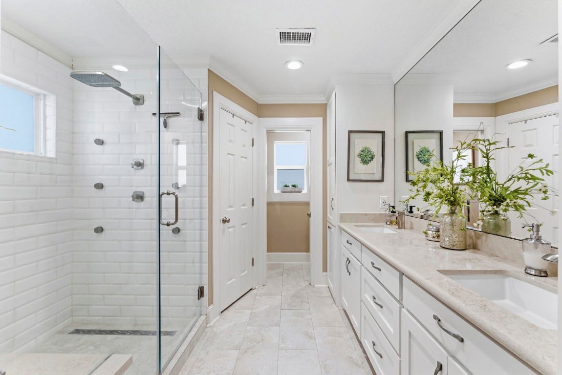 20 Falling Star Road The Woodlands, TX 77381 - Photo 22 of 44 The primary bathroom features a spacious walk-in shower with glass doors and modern fixtures. It has dual sinks set in a light countertop with ample cabinet space. The room is bright and airy, complemented by tasteful decor and neutral tones.