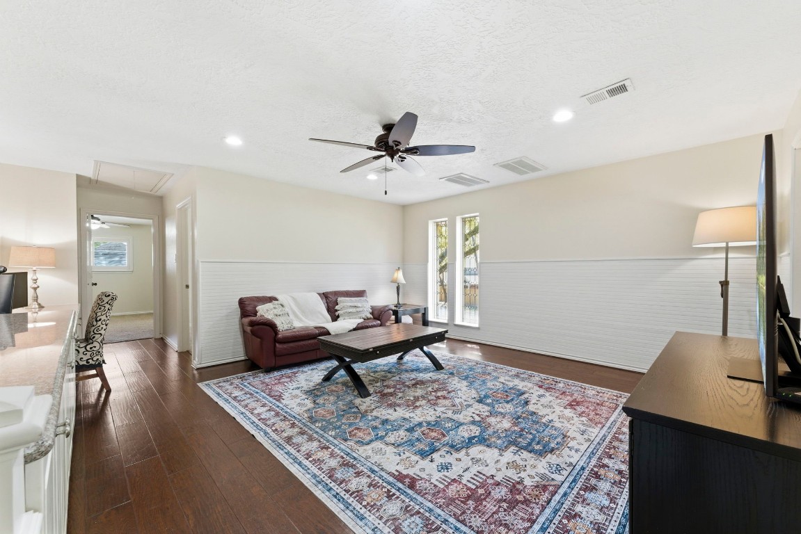 20 Falling Star Road The Woodlands, TX 77381 - Photo 24 of 44 This spacious game room features hardwood floors, a ceiling fan, and abundant natural light. It includes a cozy seating area with a plush sofa, a coffee table on a patterned rug, and a nearby home office nook.