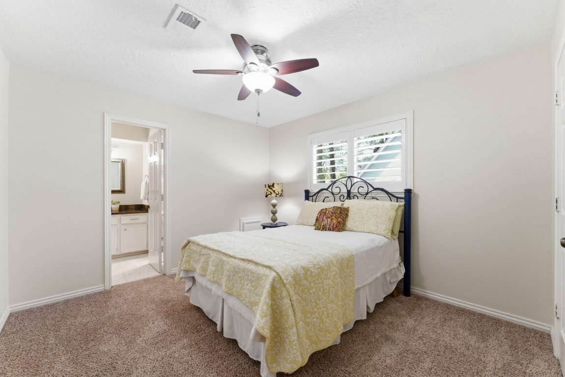20 Falling Star Road The Woodlands, TX 77381 - Photo 27 of 44 Secondary bedroom #1 has plush carpeting, featuring a ceiling fan and natural light from a window with shutters. Includes an en-suite bathroom for convenience.