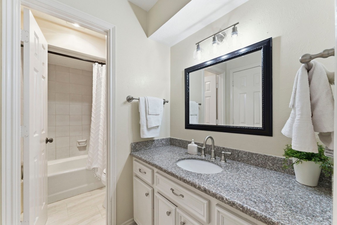20 Falling Star Road The Woodlands, TX 77381 - Photo 32 of 44 This hollywood bath features a granite countertop with a large mirror, ample cabinet storage, and a tub-shower combination. The neutral color palette and modern fixtures create a clean and inviting space.