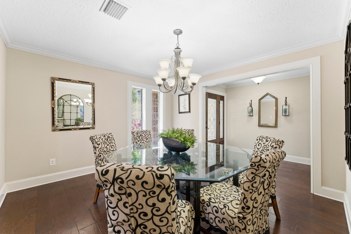 20 Falling Star Road The Woodlands, TX 77381 - Photo 6 of 44 This dining room features a stylish chandelier and warm wood flooring. The space is bright, with light walls and decorative mirrors enhancing the room's charm.