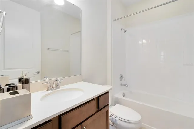 a bathroom with a bathtub shower sink vanity mirror and toilet