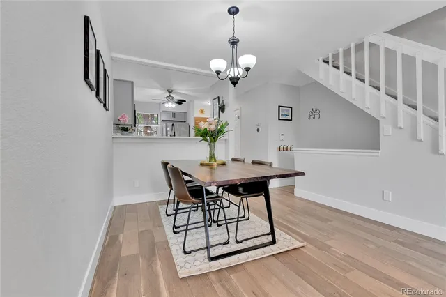 a dining room with wooden floor a chandelier a wooden table and chairs