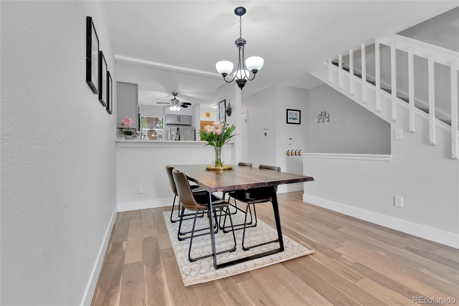 1818 South Quebec Way, Unit 46 Denver, CO 80231 - Photo 9 of 34 a dining room with wooden floor a chandelier a wooden table and chairs