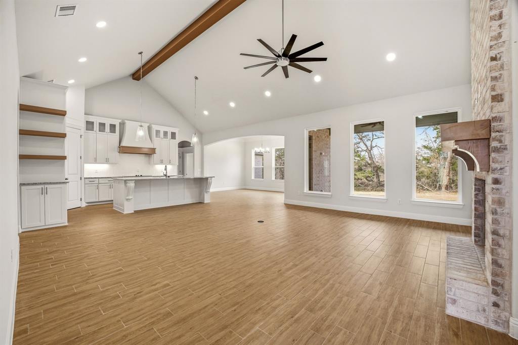 2017 Forest Bridge Azle, TX 76020 - Photo 8 of 30 Unfurnished living room featuring arched walkways, wood tiled floors, a ceiling fan, recessed lighting, and a brick fireplace